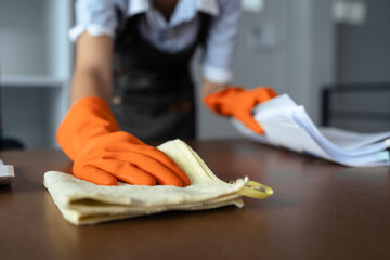 Woman maid cleaning and wiping the table with microfiber cloth in office