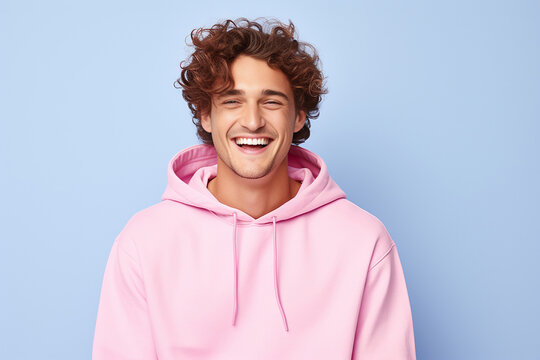 The portrait of a cute and handsome male teeager in a pink, blue hoodie standing and looking at the camera, isolated on a pink, blue background. Generative AI.