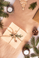 Packing a gift for Christmas and new year in eco-friendly materials: kraft paper, live fir branches, cone, twine. Tags with mock up, natural decor, hand made, flatlay. Festive mood