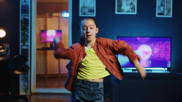 Energetic young girl filming dance tutorial for other children watching her online social media content. Happy little influencer recording video targeting generation Z viewership