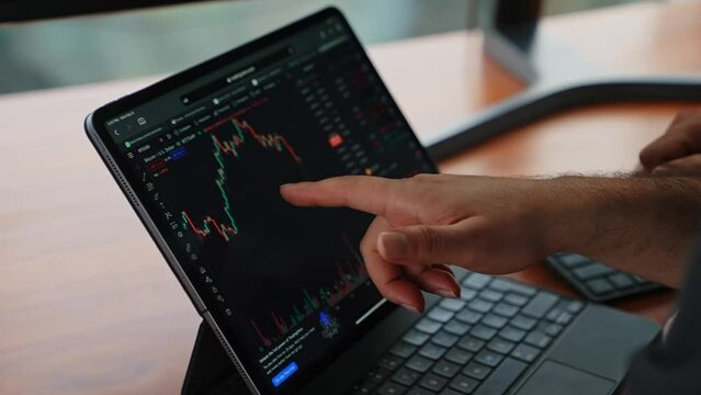 person pointing hand on a trading chart screen