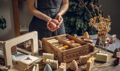 A woman soap maker holds soap in her hands in the form of colorful coniferous cones. An interesting gift for New Year's holidays and Christmas. Eco-friendly natural handmade cosmetics
