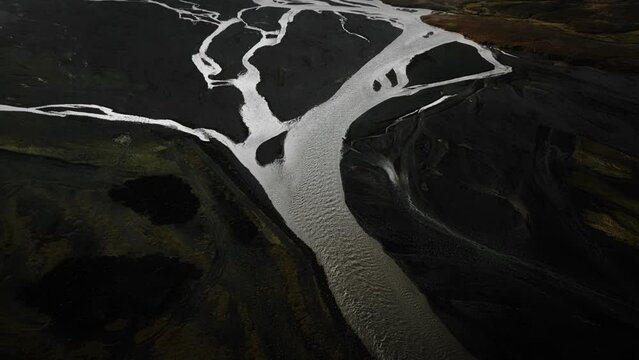 Aerial tilt up thor valley, flying over glacial river flowing through black volcanic mountains, thorsm&ouml;rk dramatic moody landscape Iceland	