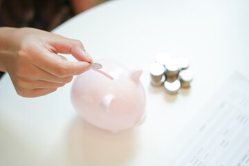 Saving money. hand putting money into pink piggy bank making investments or strategy for personal savings