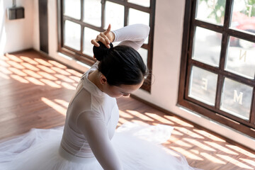 Asian girl ballet dancer preparing fixing her hair into a bun during ballet class. ballerina adjusting her hair  - Powered by Adobe