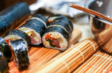 kimbap making, a cherished Korean culinary tradition. Skilled hands roll rice, vegetables, and seaweed, crafting delicious, nutritious bites for an authentic dining experience