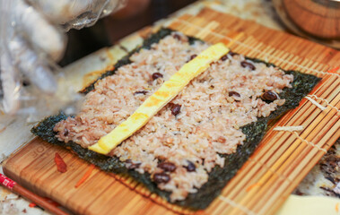 kimbap making, a cherished Korean culinary tradition. Skilled hands roll rice, vegetables, and seaweed, crafting delicious, nutritious bites for an authentic dining experience