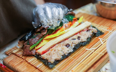 kimbap making, a cherished Korean culinary tradition. Skilled hands roll rice, vegetables, and...
