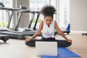 Vibrant, energetic woman utilizing a laptop to work out at home and watching online classes....