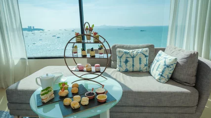 Fotobehang afternoon tea or high tea in a hotel room with bright fresh colors, a minimal style bedroom with an ocean view © Chirapriya