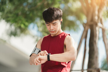 Asian man using app on smart watch for select music, Measure your heartbeat, and calories burned....
