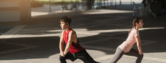 Young Asian couple stretching together before jogging exercise in urban area. Warming up for...