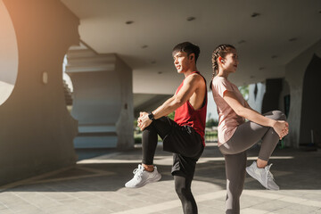 Obraz premium Young Asian couple stretching together before jogging exercise in urban area. Warming up for workout outdoor in the morning.