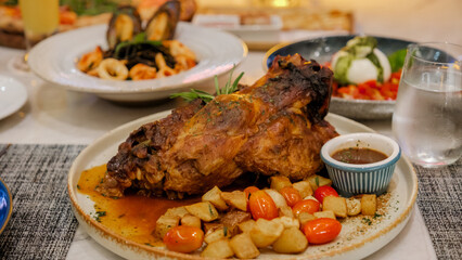 dinner in an Italian restaurant in Thailand, slow cooked pork, Whole roast shoulder of pulled pork with rich spicy hot marinade on a table with chili, garlic, and rosemary. view from above, close-up