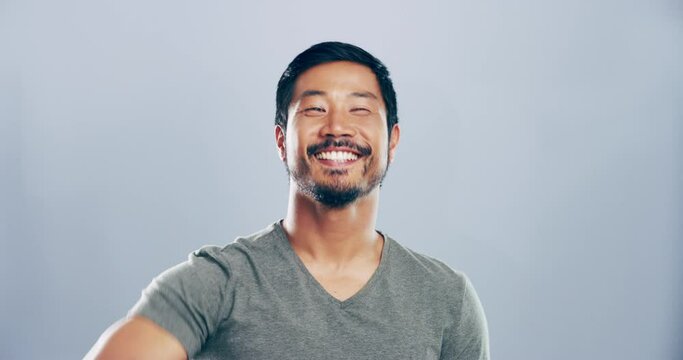 Portrait, rock and roll with Asian man, energy and artist with attitude on grey studio background. Face, Japanese person and model with creativity, hand sign or culture with punk or heavy metal music