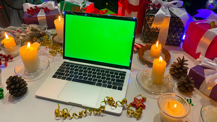 Freelancer's desktop decorated with New Year's gifts, burning candles, cones, confetti, fir...