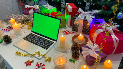 New Year's background. Festive Christmas table with a laptop with a chroma key on the screen....