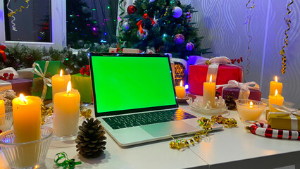 Magical Christmas concept. Chroma key. Christmas table with a laptop with a green screen, New...