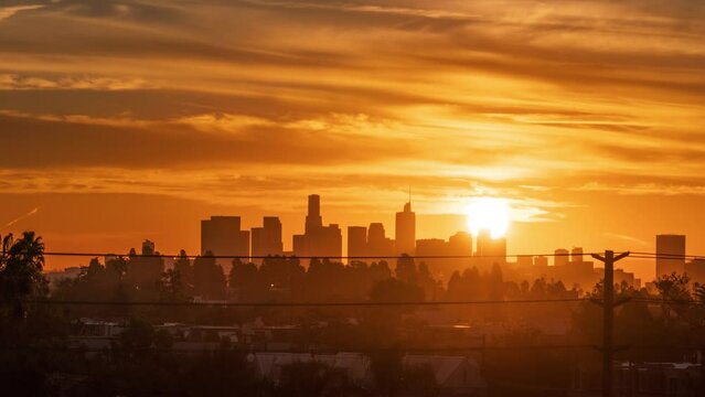 Sunrise over downtown Los Angeles skyline. Dramatic orange clouds moving over city scape silhouette. Timelapse.