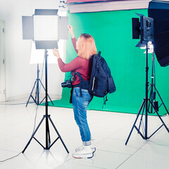 Confident Young female photographer fixing photography lights in a photo studio