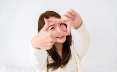 Fototapeta premium Young asian woman happy and making frame with fingers on white background in house
