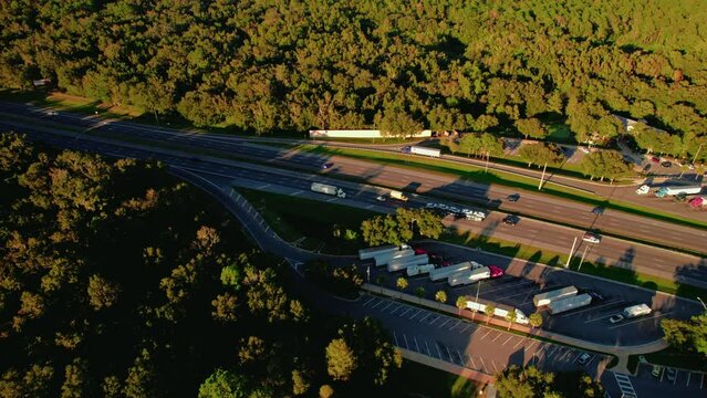 orbiting aerial following a semi truck exiting rest area stop after 10 hours of sleep