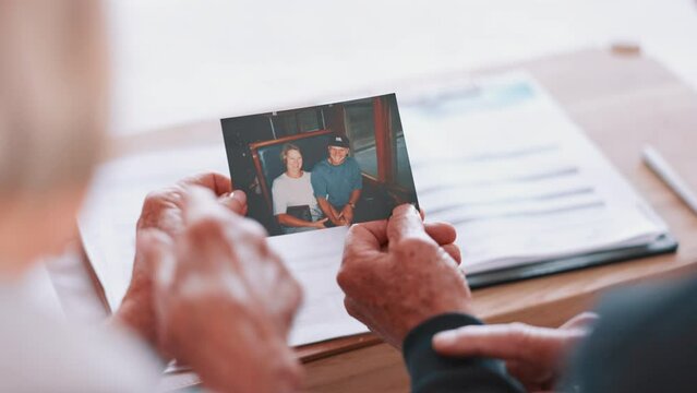 Photograph, memory and old couple in home remember date, event and marriage with nostalgia. Elderly people back, hands and photography as a reminder of life in vintage picture and thinking of history