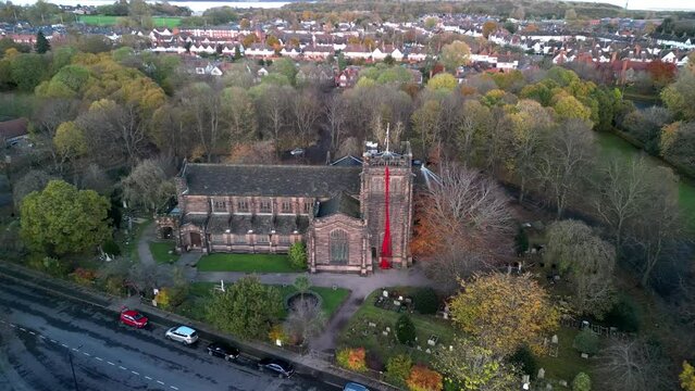 River of poppies commemorating sacrifice. 3,500 knitted poppies at Christ Church, Port Sunlight, UK - aerial drone move in, memorial closeup