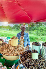 woman street african vendor selling mopane worms, raw peanuts and raisins