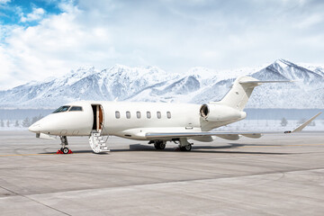 Modern white business jet with an opened gangway door at the winter airport apron on the background...