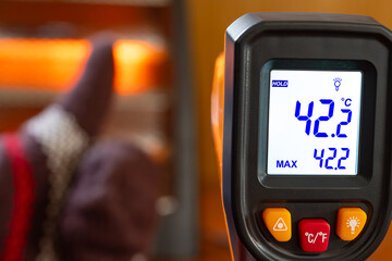 infrared thermometer shows the temperature of a glove with thumbs up gesture in front of an...