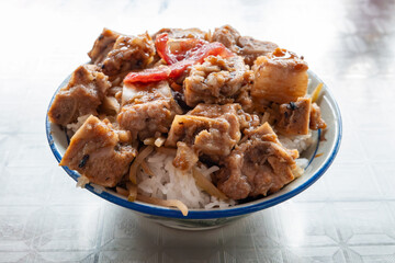 angle view bowl of rice with pork ribs and slices of Chinese style sausage