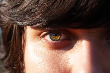 young man face with green eyes close up on pupil