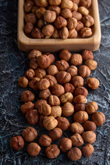 Top view of ripe hazelnuts randomly arranged on a textured gray background. Delicious roasted hazelnuts on the table and in a wooden bowl