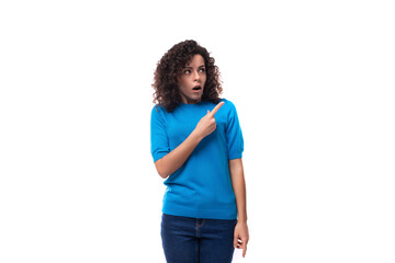 bright curly woman dressed in a blue summer jacket holds her index finger up