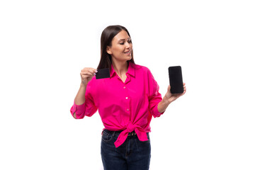 charming young brunette businesswoman dressed in a pink shirt shows the smartphone screen