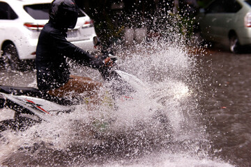 Season Monsoon. Heavy rain and water logging on road.  Motor bike.