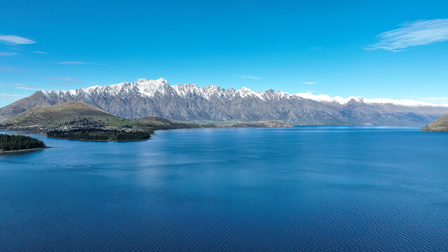 Drone panoramic view of the bays and inlets at Queenstown town at the southern end of Lake Wakatipu with a backdrop of the snow capped Remarkables Mountain range