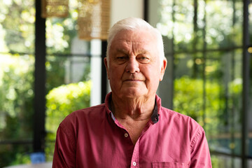 Portrait of happy caucasian senior man smiling in sunny kitchen at home