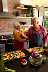  Happy caucasian senior couple putting on aprons, preparing vegetables in kitchen, copy space © WavebreakMediaMicro
