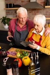  Happy caucasian senior couple preparing vegetables, drinking wine and using tablet in kitchen © WavebreakMediaMicro