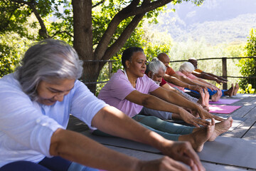 Happy diverse group of senior friends stretching at yoga class in sunny garden, copy space - Powered by Adobe