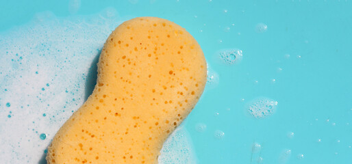 Yellow sponge with bubbles on blue background