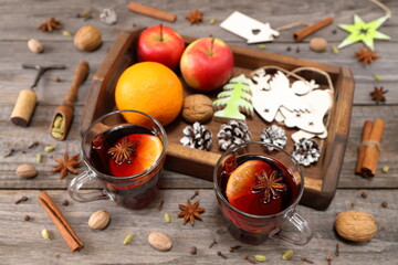 Christmas mulled wine. A pair of glass mugs of mulled wine next to a wooden tray with fruit and...