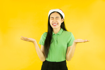 Fototapeta na wymiar portrait of happy asian woman wears a christmas red santa claus hat isolated on yellow background