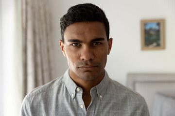 Portrait of biracial man with black hair standing in bedroom at home