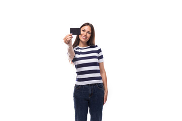 charming young european woman with black straight hair in a striped black and white t-shirt and jeans enjoys online payments using credit card details