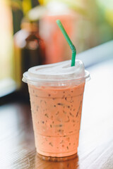 Iced coffee in a plastic cup on a wooden table in a cafe.