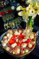 A bowl of ice cubes with frozen flowers and berries. 
