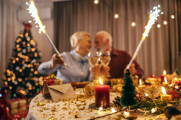 Selective focus on christmas decorations on table at home with blurry senior couple celebrating...
